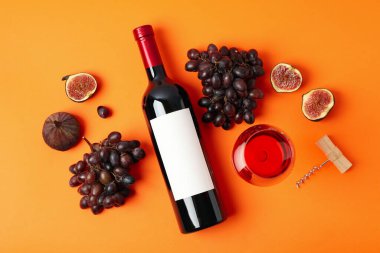 Turuncu arka planda şarap, incir ve üzümlü kompozisyon.