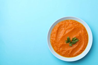 Mavi arka planda kabak püresi ve maydanozlu tabak.