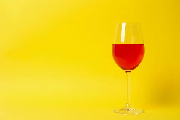 Glass of wine on yellow background, space for text