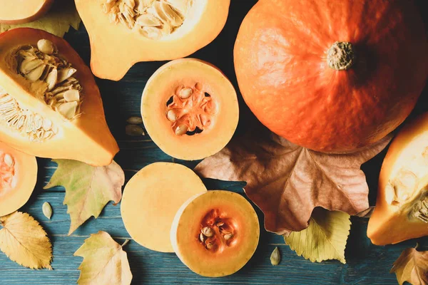 Composition with pumpkin, squash, seeds and leaves on wooden background
