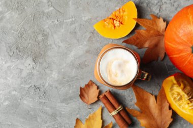 Gri masada balkabağı latte, balkabağı, yapraklar ve tarçınlı kompozisyon