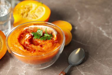 Gri arkaplanda bir kase kabak çorbası ile kompozisyon, metin için boşluk