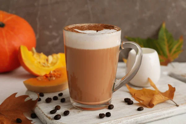 Composition with glass cup of pumpkin latte on white background