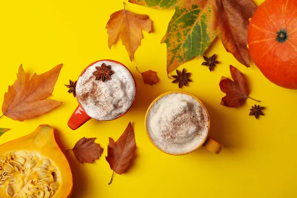 Composition with pumpkin latte, cinnamon, leaves and pumpkin on yellow background