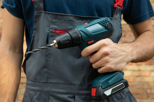 Man Overalls Holds Cordless Drill Brick Wall Background — Stock Photo, Image