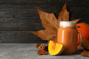 Gri masada balkabağı latte, balkabağı, yapraklar ve tarçınlı kompozisyon