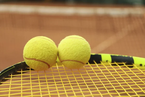 Tennis racquet with tennis balls against clay court