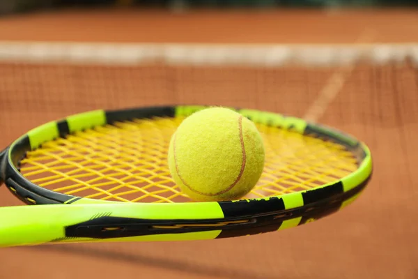 Tennis racquet with tennis ball against clay court