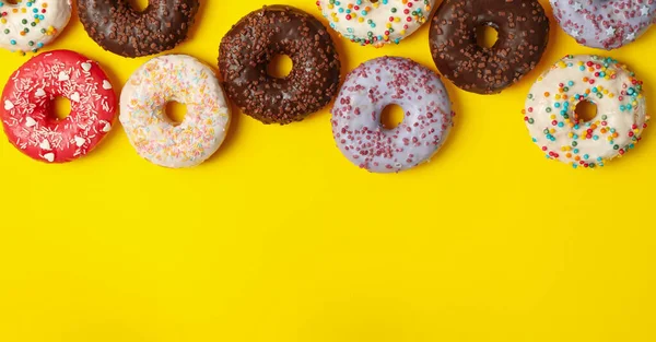 Verschiedene Leckere Donuts Auf Gelbem Hintergrund Draufsicht — Stockfoto