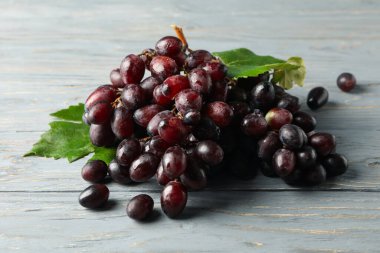 Gri ahşap arka planda yaprakları olan olgun üzümler.