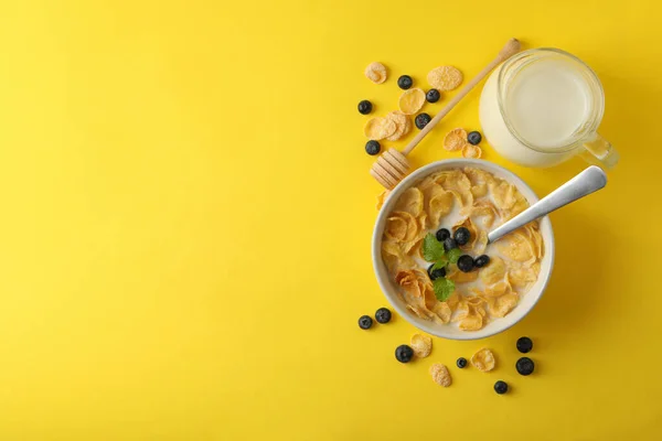 Milk, bowl of muesli and dipper on yellow background