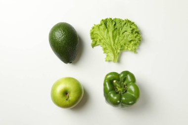 Beyaz arka planda avokado, elma, salata ve biber.