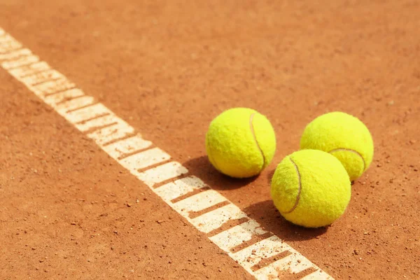 Light green tennis balls on clay court