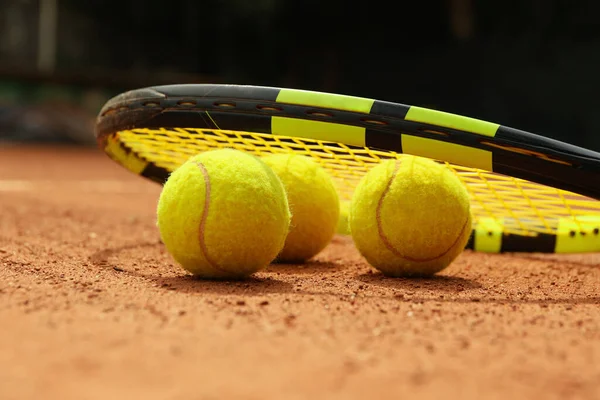 Racket and tennis balls on clay court