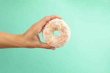 Kadın eli, arka planda lezzetli bir donut tutuyor.