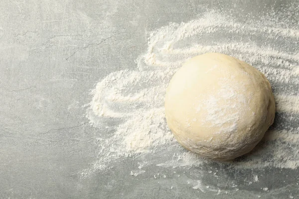 Dough ball and flour on gray background