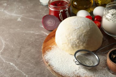 Gri arka planda pizza pişirmek için hamur ve malzemeler.