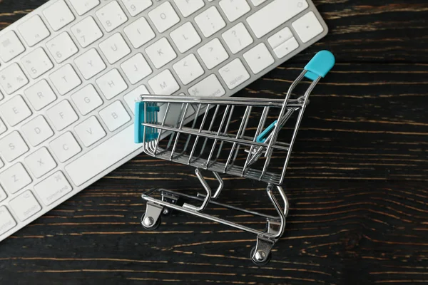 Shop cart and keyboard on wooden background