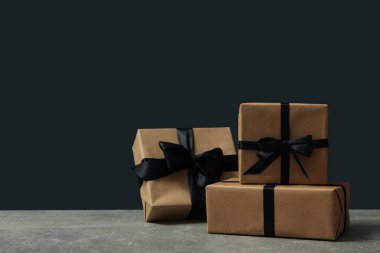 Siyah arkaplana karşı gri masa üzerinde fiyonklu el işi hediye kutuları