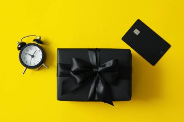 Hediye kutusu, alarm saati ve sarı arka plandaki kart.