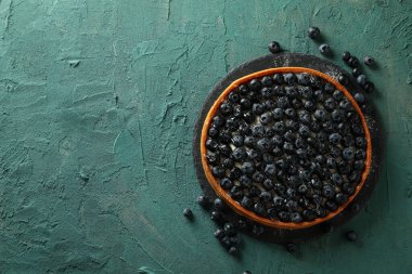 Yeşil arkaplanda yabanmersinli turta tepsisi