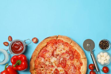 Lezzetli pizza ve malzemeler mavi arka planda.