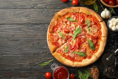 Lezzetli pizza ve ahşap arka planda malzemeler