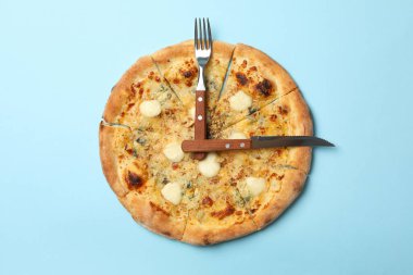 Mavi arka planda pizza ve çatal bıçaktan yapılmış saat.