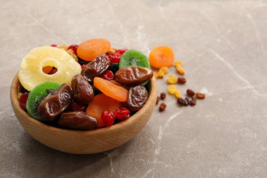 Gri arka planda kurumuş meyveler olan ahşap bir kase.