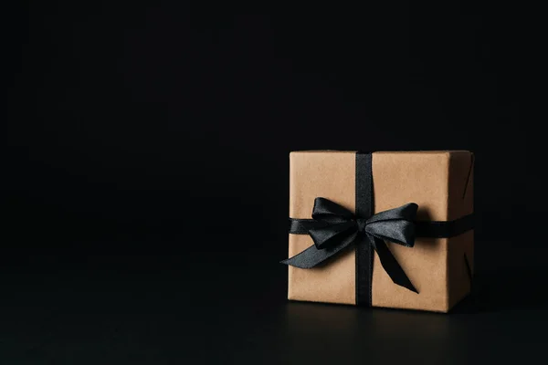 Gift box with black bow on black background