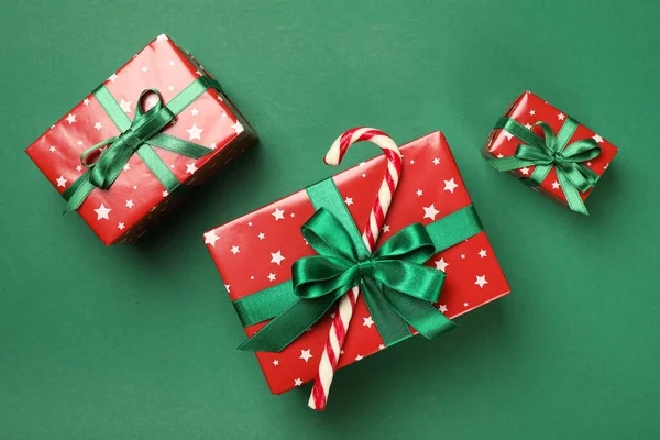 Christmas boxes and candy cane on green background