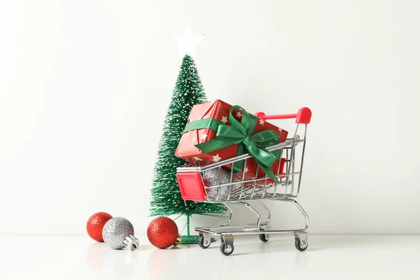 Shop cart with gift box and Christmas accessories on white background