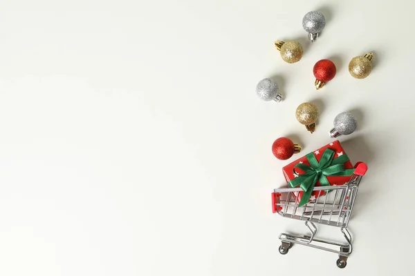 Shop cart with Christmas box and baubles on white background