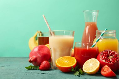 Yeşil arka planda farklı meyve suları bulunan bardak ve şişe kavramı