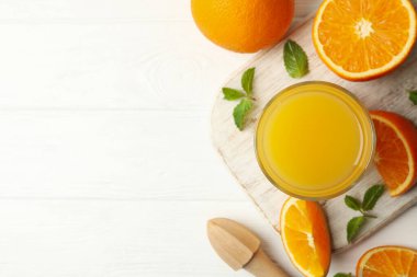 Ahşap zemin üzerinde bir bardak portakal suyu, portakal suyu ve meyve sıkacağı olan tahta.