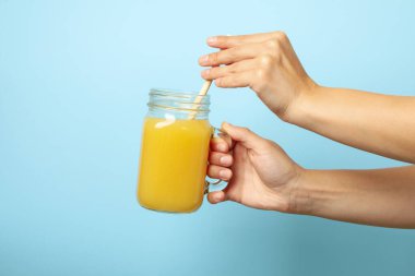 Kadın eli mavi arka planda muz suyu tutar