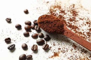 Kahveli kaşık ve beyaz arka planda fasulye.