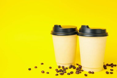 Sarı arkaplanda kağıt bardaklar, metin için boşluk