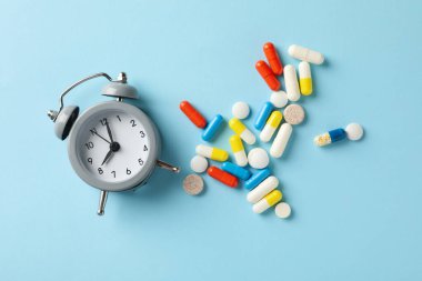 Alarm saati ve mavi arkaplanda haplar