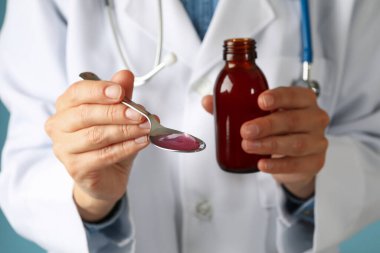 Doktor şişeyi ve kaşığı şurupla tut, kapat.