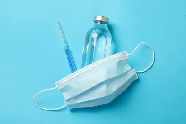 Medical mask and medicines on blue background