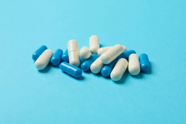 Pills capsules on blue background, space for text