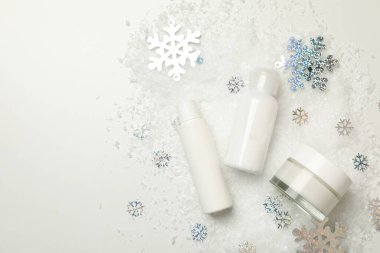 Dekoratif kar ile beyaz arkaplanda kozmetik ürünler