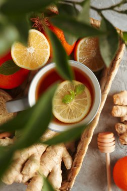 Gri arkaplanda zencefil, portakal, tarçın, limon ve çay sepeti