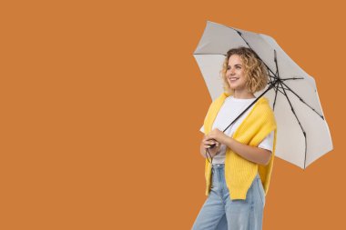 Bir kadın şemsiyesini açık havada tutarken anın tadını çıkarıyor.