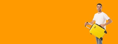 Genç adam macera için parlak bir bavulla gülümsüyor.