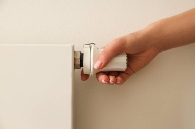 Birisi ısı kontrolü için radyatör vanasını ayarlıyor.