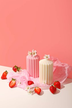 Pembe ve beyaz gölgeli mumlar taze çileklerle çevrilidir.