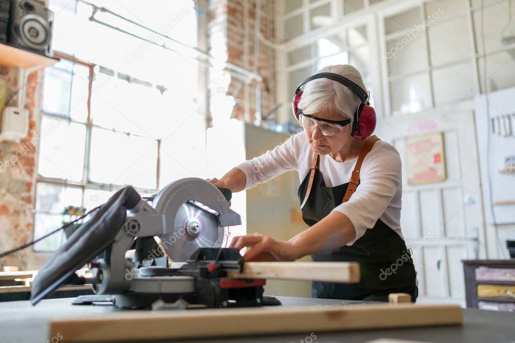 Senior woman doing woodwork in a workshop