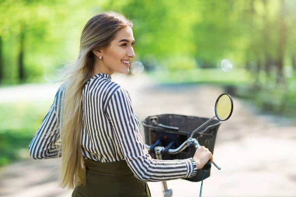 有魅力的年轻女子骑车穿过公园 — 图库照片